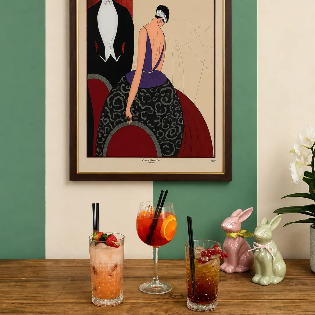 Tre cocktail su tavolo in legno, con fragole e arancia; sullo sfondo poster e coniglietti decorativi